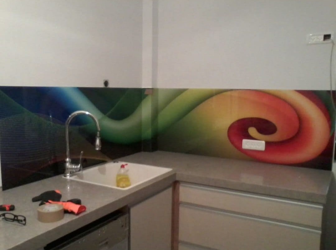 A kitchen backsplash with flowing bands of red, yellow, green, and blue.